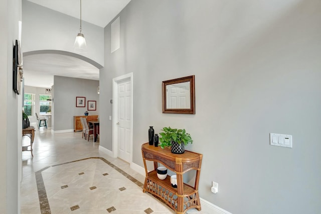 foyer entrance featuring arched walkways, a high ceiling, and baseboards