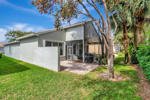 back of house with a lanai, a patio area, a lawn, and stucco siding