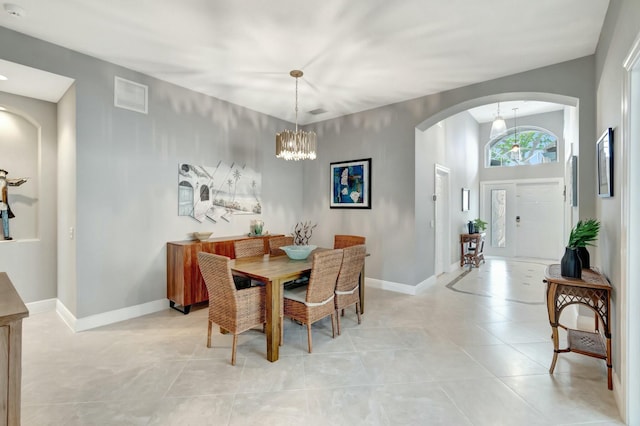 dining space featuring light tile patterned floors, baseboards, visible vents, arched walkways, and a notable chandelier