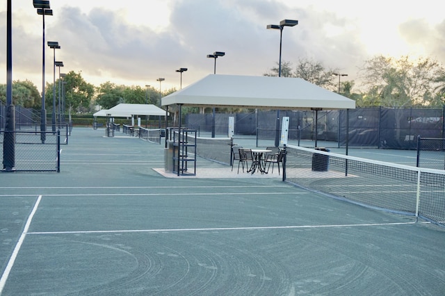 view of home's community with a tennis court and fence