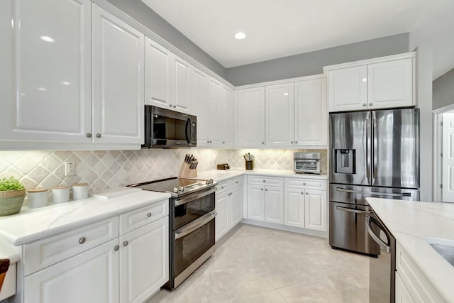 kitchen with light stone counters, recessed lighting, stainless steel appliances, white cabinetry, and tasteful backsplash