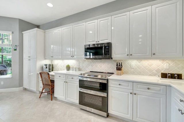 kitchen featuring white cabinetry, stainless steel appliances, backsplash, and light countertops