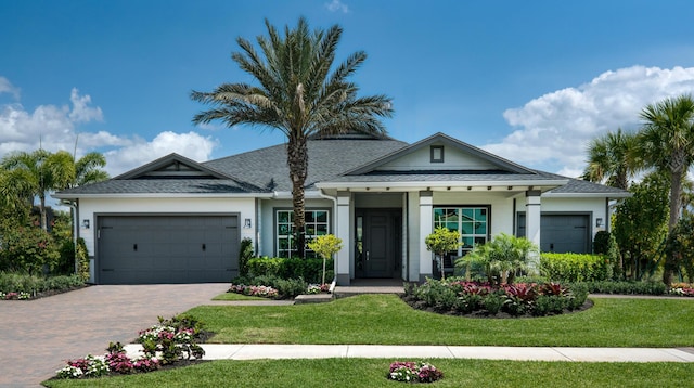 view of front of property with decorative driveway, an attached garage, and a front yard