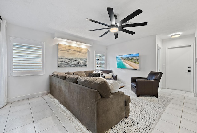 living room featuring ceiling fan, baseboards, a textured ceiling, and light tile patterned flooring