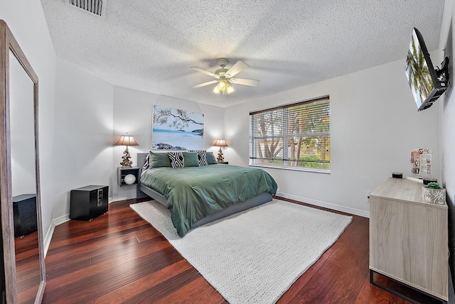 bedroom featuring baseboards, visible vents, ceiling fan, dark wood-style flooring, and a textured ceiling