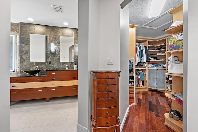 spacious closet with light wood-style floors, visible vents, arched walkways, and a sink