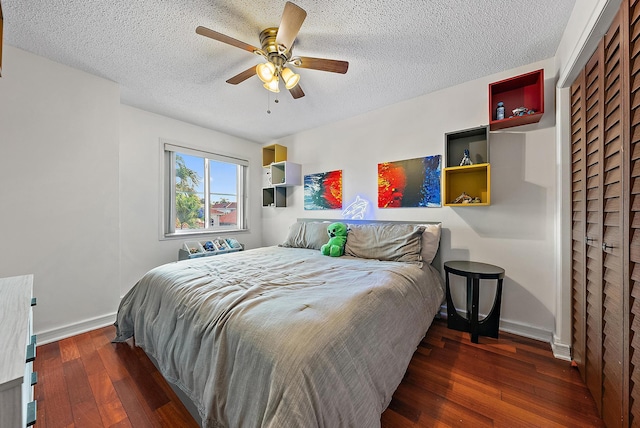 bedroom featuring dark wood-style floors, ceiling fan, a textured ceiling, and baseboards