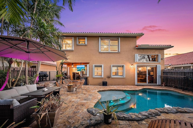 back of house at dusk with a fenced backyard, an outdoor living space, a patio, and stucco siding