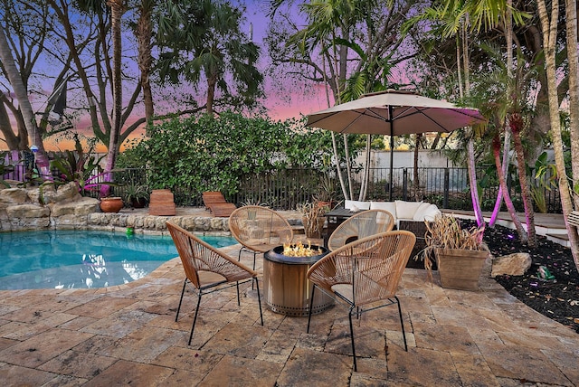 patio terrace at dusk with a fire pit, a fenced backyard, and a fenced in pool