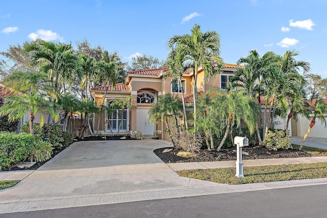 mediterranean / spanish-style home with concrete driveway, a tile roof, and stucco siding