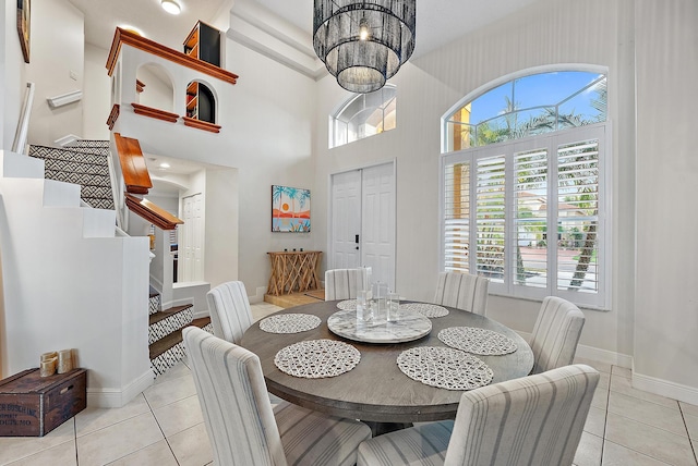 dining room with a notable chandelier, stairway, baseboards, and light tile patterned floors