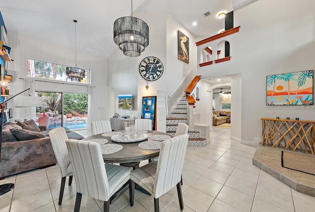 dining room with light tile patterned floors, visible vents, baseboards, stairs, and ceiling fan with notable chandelier