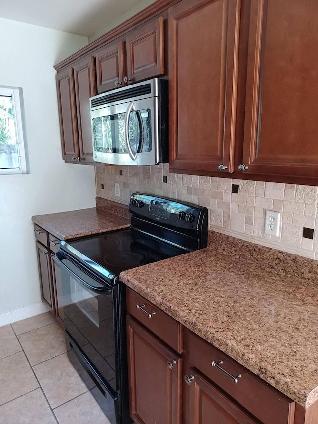 kitchen with light tile patterned floors, electric range, baseboards, tasteful backsplash, and stainless steel microwave