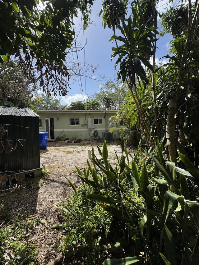 rear view of property featuring cooling unit, an outdoor structure, and a storage shed
