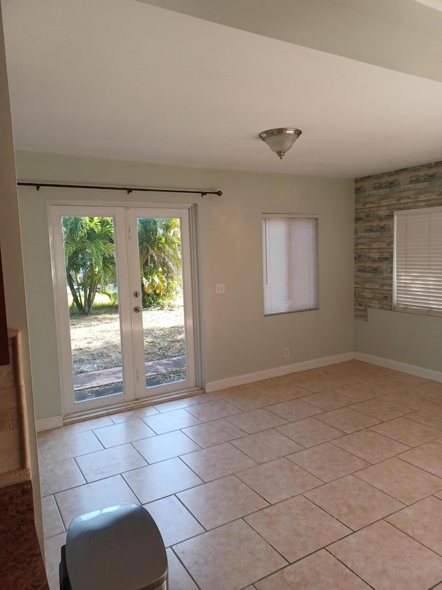 unfurnished room with light tile patterned floors, baseboards, and french doors