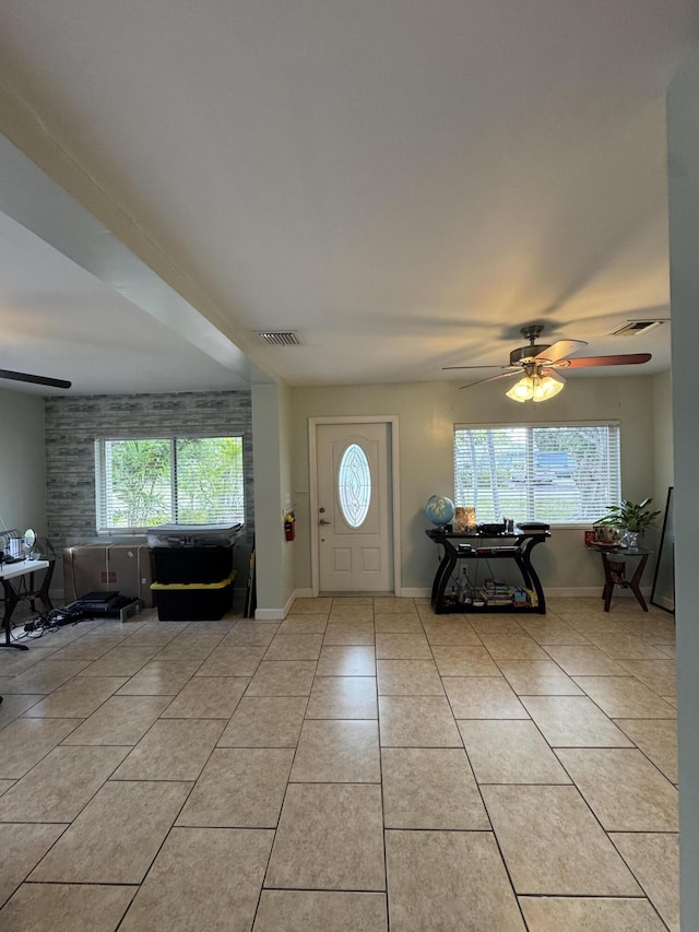 tiled foyer entrance with baseboards, ceiling fan, and visible vents