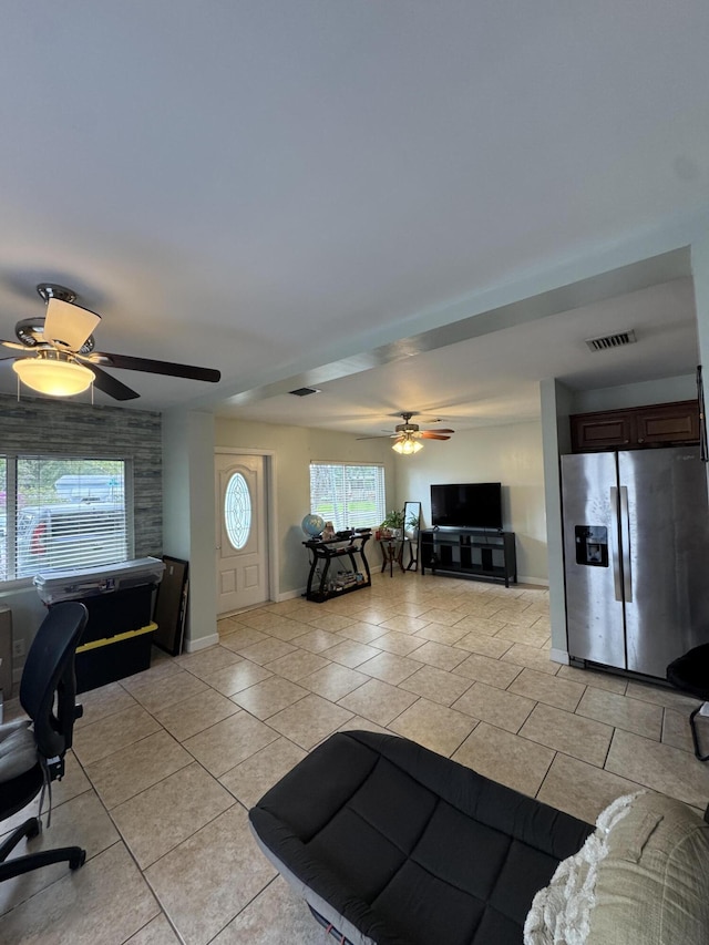 living area featuring light tile patterned flooring, baseboards, visible vents, and a ceiling fan