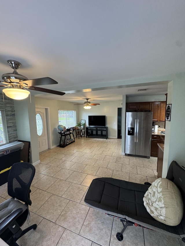 living room with light tile patterned flooring, baseboards, visible vents, and a ceiling fan