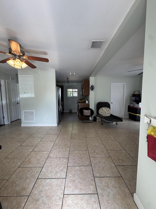 unfurnished living room with a ceiling fan, light tile patterned floors, baseboards, and visible vents