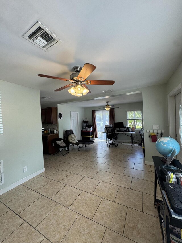 living area with baseboards, visible vents, light tile patterned floors, and a ceiling fan