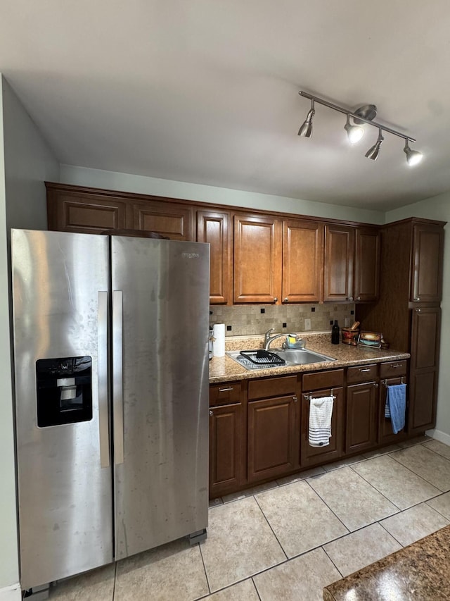 kitchen with backsplash, light tile patterned floors, a sink, and stainless steel fridge with ice dispenser