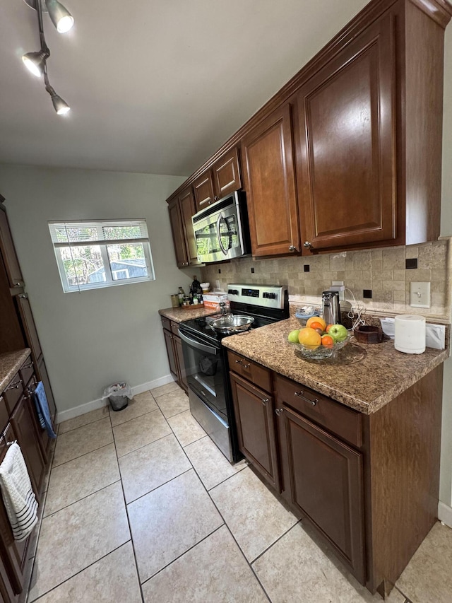 kitchen with light tile patterned floors, appliances with stainless steel finishes, baseboards, and decorative backsplash