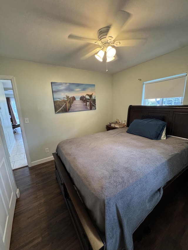 bedroom with baseboards, dark wood-type flooring, and a ceiling fan