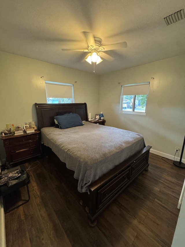 bedroom featuring dark wood-style flooring, baseboards, ceiling fan, and visible vents