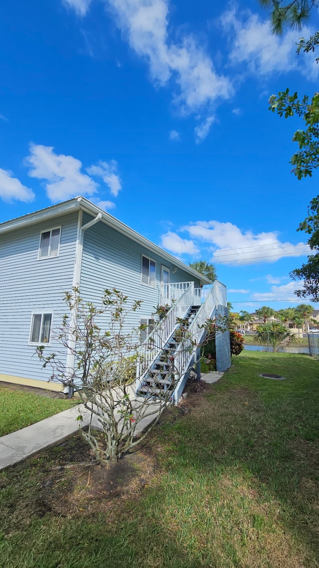 view of side of property with stairs and a yard