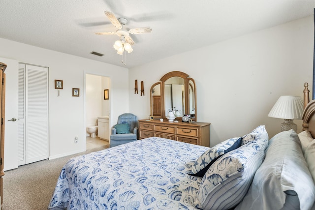 carpeted bedroom with a textured ceiling, ceiling fan, connected bathroom, visible vents, and baseboards