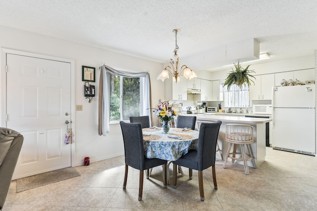 dining area featuring a textured ceiling, baseboards, and an inviting chandelier