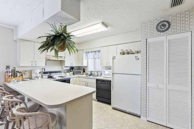 kitchen with white appliances, visible vents, a peninsula, a textured ceiling, and a sink