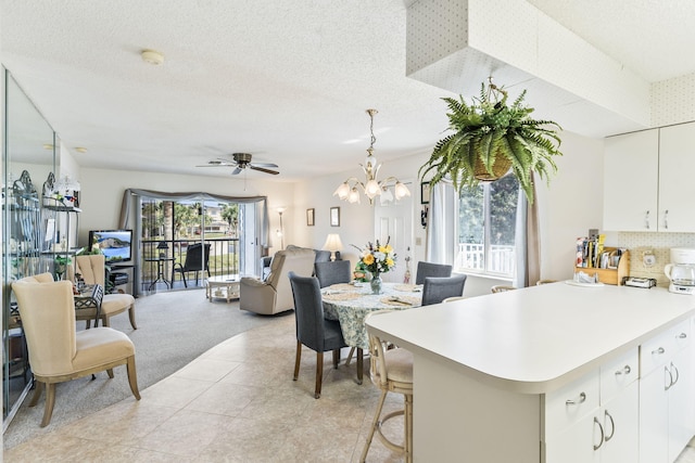 kitchen with open floor plan, light countertops, white cabinetry, and a ceiling fan