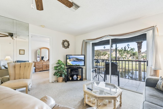 carpeted living room with a textured ceiling, visible vents, and a ceiling fan