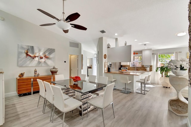 dining space featuring lofted ceiling, visible vents, and light wood finished floors