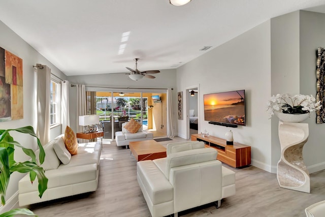 living area featuring lofted ceiling, light wood-style flooring, baseboards, and ceiling fan