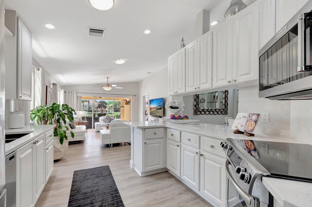 kitchen with a sink, white cabinetry, appliances with stainless steel finishes, decorative backsplash, and light stone countertops