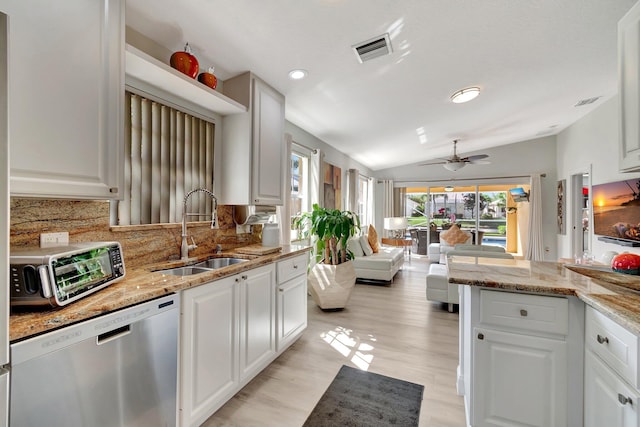 kitchen with visible vents, backsplash, vaulted ceiling, a sink, and dishwasher