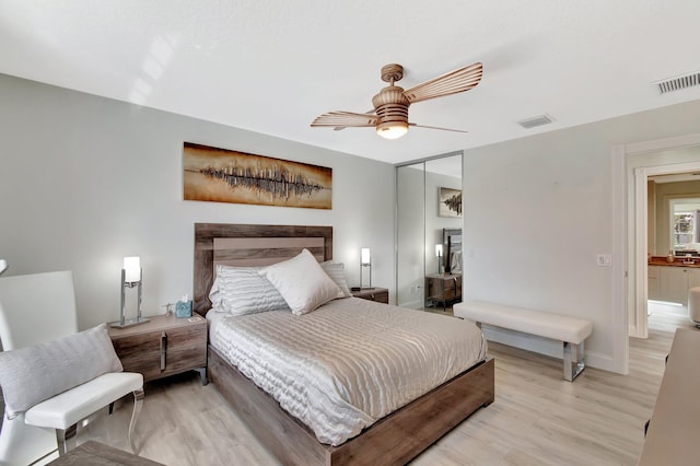 bedroom featuring light wood finished floors, visible vents, baseboards, ceiling fan, and a closet