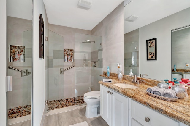 bathroom featuring visible vents, vanity, a shower stall, and toilet