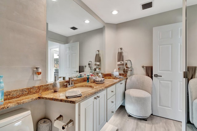 bathroom with toilet, visible vents, wood finished floors, and vanity