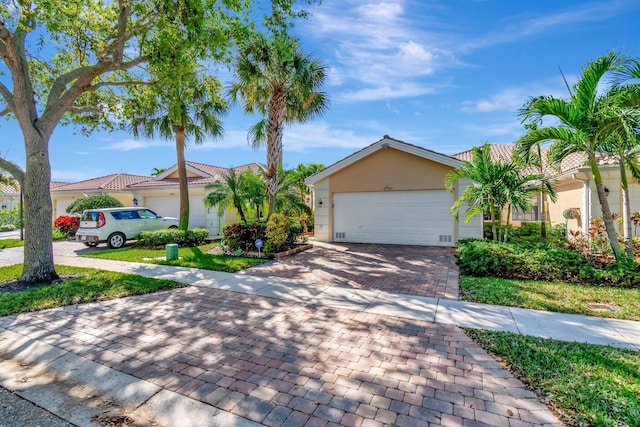 view of front of house with decorative driveway, an attached garage, and stucco siding