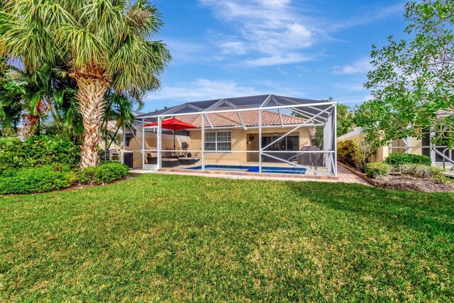 rear view of property featuring glass enclosure, an outdoor pool, a lawn, and a patio