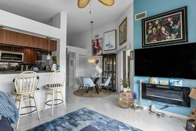 living room featuring ceiling fan, high vaulted ceiling, tile patterned flooring, and visible vents