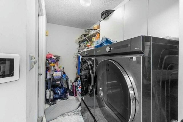 clothes washing area with laundry area, washing machine and dryer, and a textured ceiling