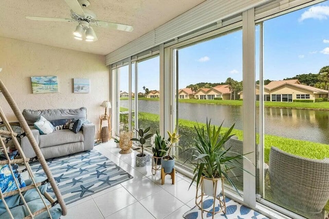 sunroom / solarium with a ceiling fan and a water view