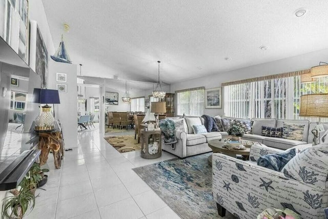 living room with light tile patterned floors, a notable chandelier, vaulted ceiling, and a textured ceiling