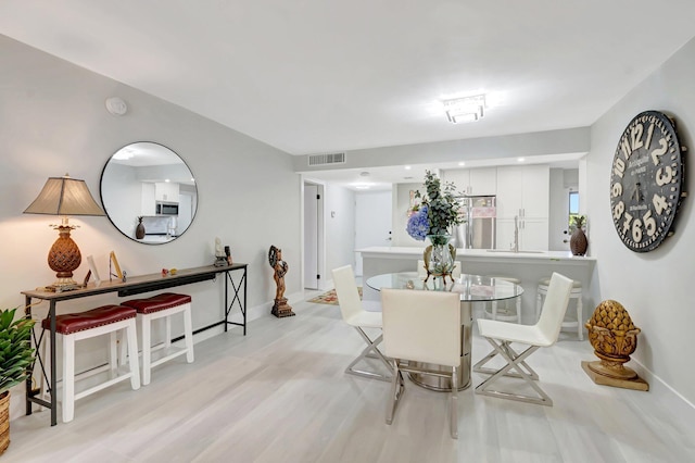 dining area featuring light wood-style floors, visible vents, and baseboards