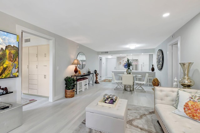 living area featuring baseboards, visible vents, and wood finished floors