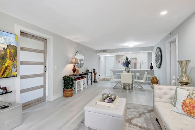 living area featuring visible vents, wood finished floors, and baseboards